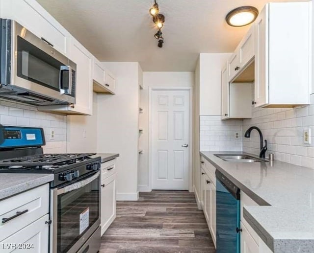 kitchen with appliances with stainless steel finishes, white cabinetry, backsplash, dark hardwood / wood-style flooring, and sink