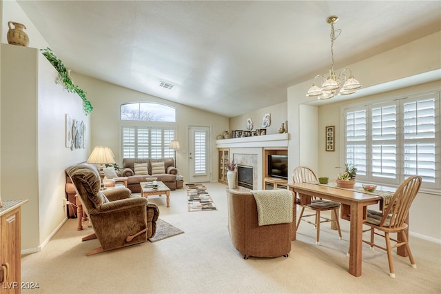 carpeted living room with a notable chandelier, vaulted ceiling, and plenty of natural light