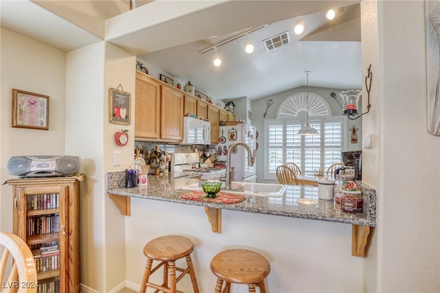 kitchen with lofted ceiling, a kitchen bar, white appliances, backsplash, and light stone countertops