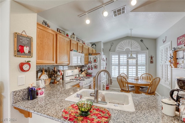 kitchen featuring light stone counters, sink, white appliances, decorative light fixtures, and vaulted ceiling