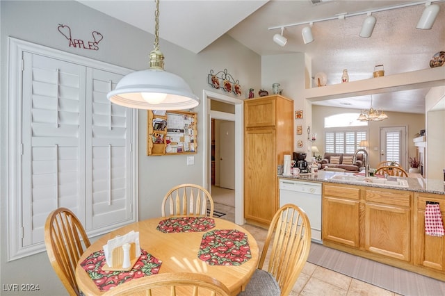 dining space with lofted ceiling, light tile patterned floors, sink, track lighting, and a notable chandelier