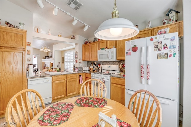 kitchen featuring light stone counters, white appliances, pendant lighting, lofted ceiling, and sink