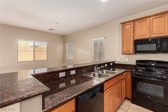 kitchen with light tile patterned flooring, sink, dark stone countertops, and black appliances