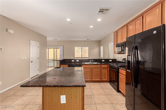 kitchen featuring sink, a kitchen island, dark stone countertops, light tile patterned flooring, and black appliances