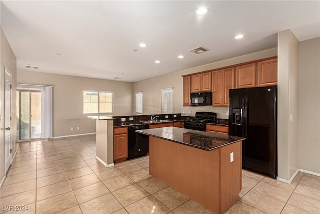 kitchen featuring black appliances, a kitchen island, kitchen peninsula, and dark stone counters