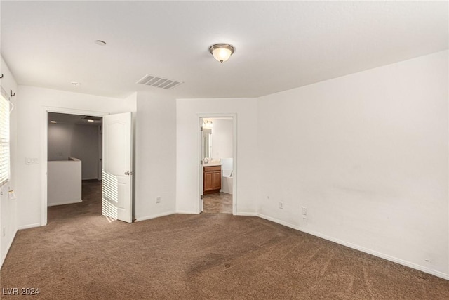 unfurnished bedroom featuring dark colored carpet and ensuite bath