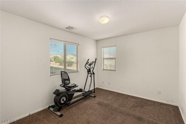 workout area with dark colored carpet and a textured ceiling