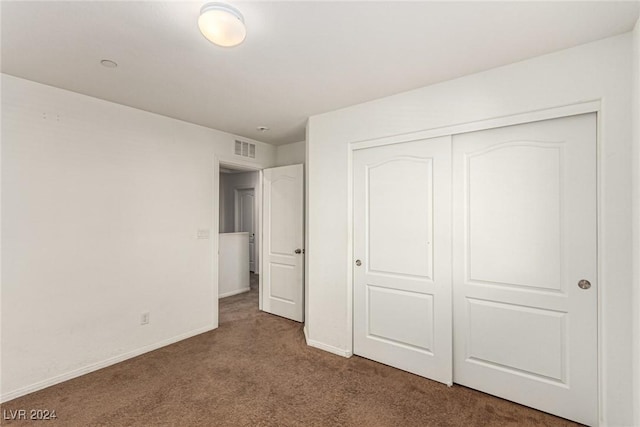 unfurnished bedroom with dark carpet and a closet