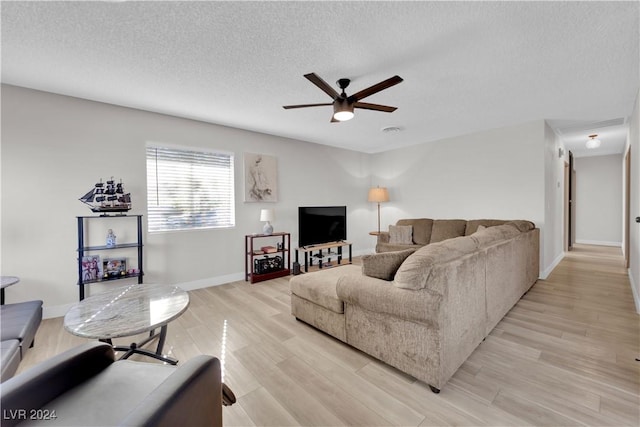 living room with ceiling fan, light hardwood / wood-style flooring, and a textured ceiling