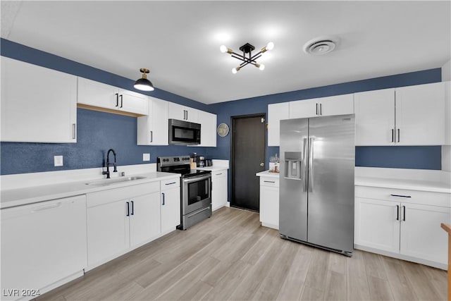 kitchen featuring appliances with stainless steel finishes, sink, white cabinets, and light hardwood / wood-style flooring