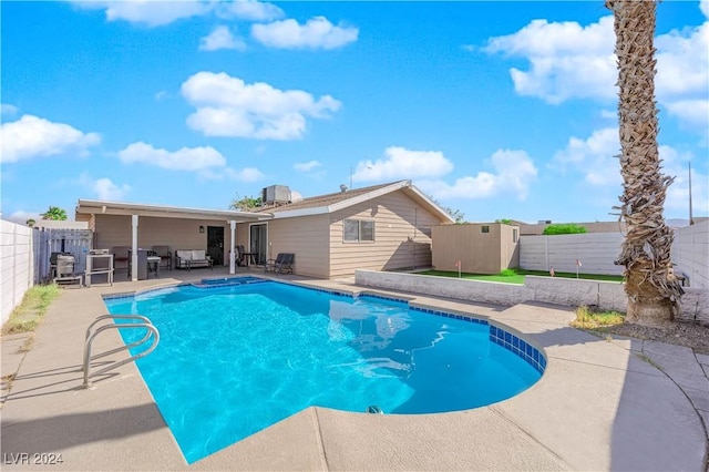 view of pool featuring an outdoor living space, a patio, and a storage shed