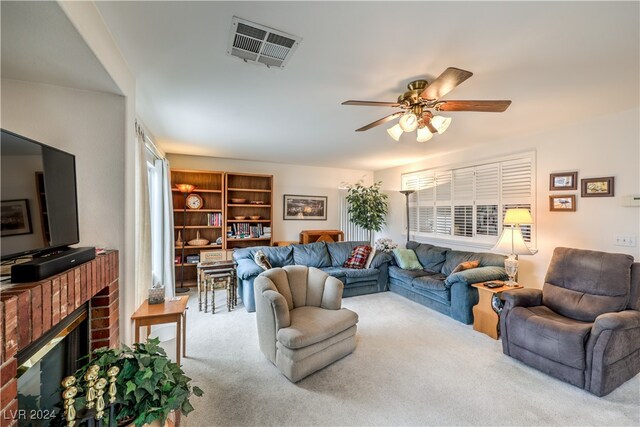 carpeted living room featuring a brick fireplace and ceiling fan