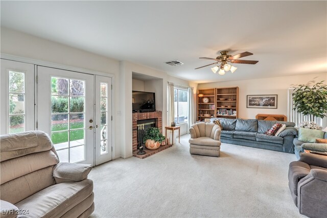 living room featuring a brick fireplace, carpet, and ceiling fan