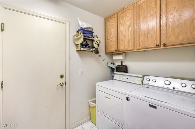 washroom with light tile patterned floors, washing machine and clothes dryer, and cabinets