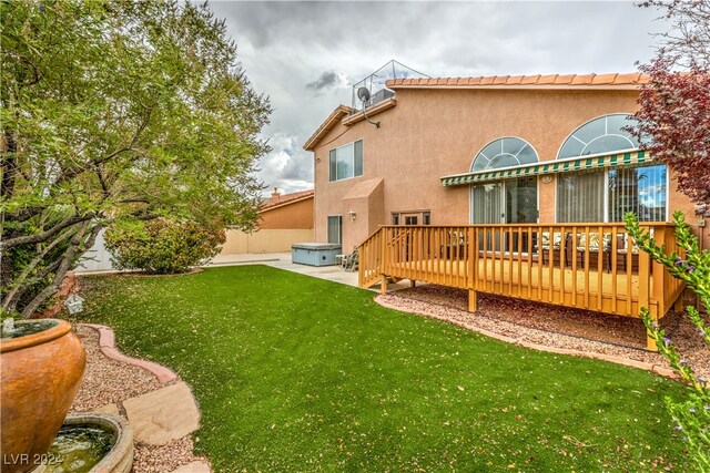 rear view of house featuring a lawn, a wooden deck, and a patio area