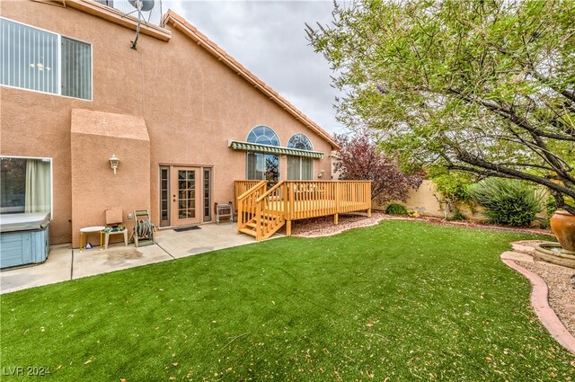 back of house featuring french doors, a deck, a lawn, and a patio area