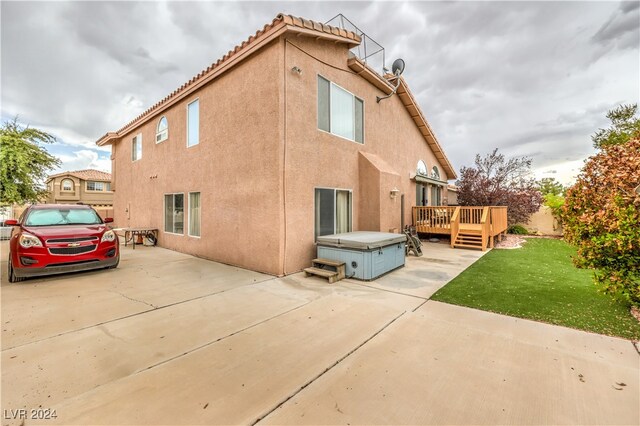 rear view of house with a wooden deck, a yard, and a patio