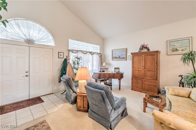 carpeted entrance foyer with high vaulted ceiling