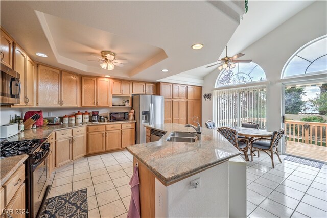 kitchen with sink, a center island with sink, appliances with stainless steel finishes, light stone countertops, and ceiling fan