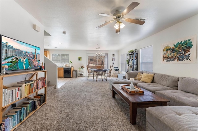 carpeted living room featuring ceiling fan with notable chandelier and a textured ceiling