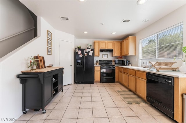 kitchen with sink, light tile patterned floors, and black appliances