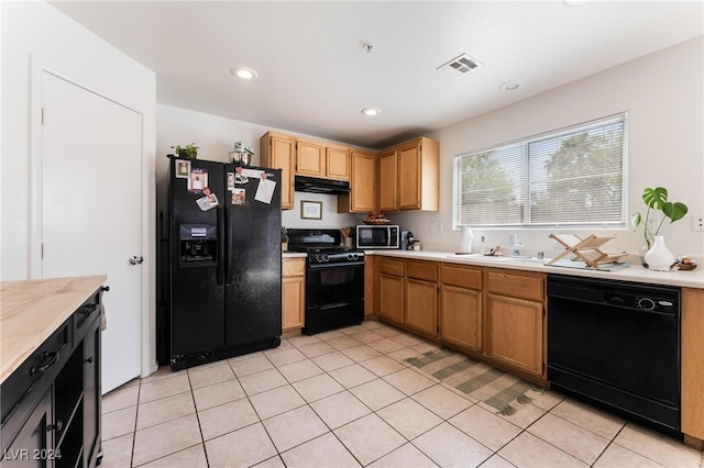 kitchen with light tile patterned flooring, sink, and black appliances