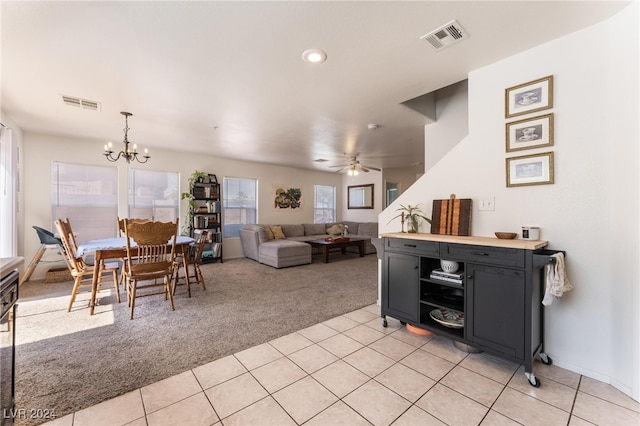 carpeted living room with ceiling fan with notable chandelier