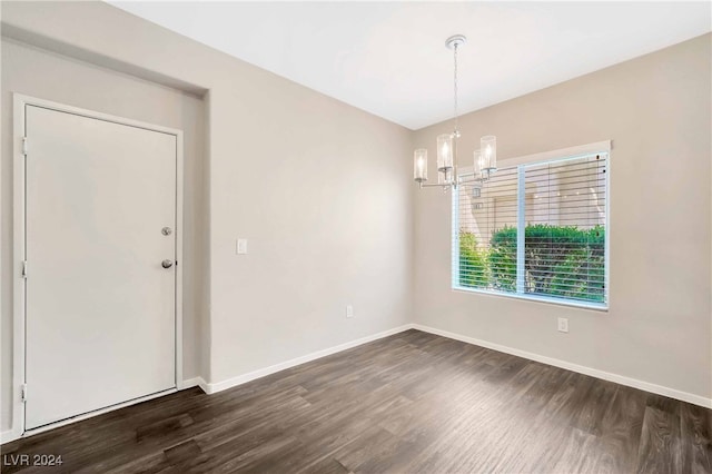 empty room featuring an inviting chandelier and dark hardwood / wood-style flooring