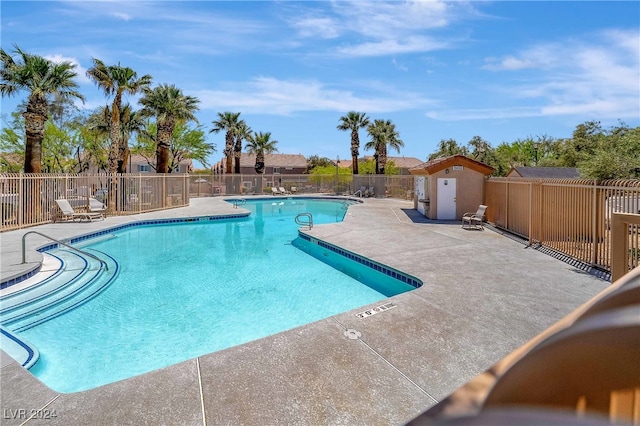 view of swimming pool with a shed and a patio area