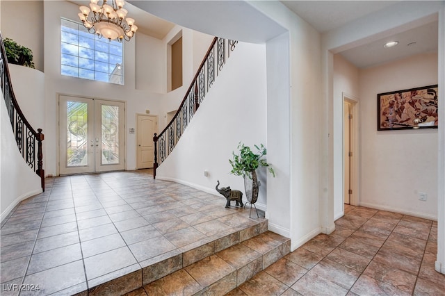 entrance foyer featuring a towering ceiling, an inviting chandelier, and french doors