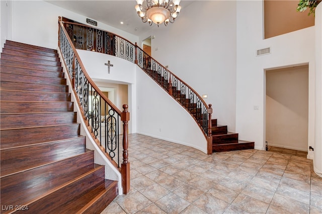 stairs with a towering ceiling and a chandelier