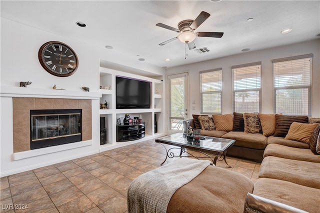 tiled living room with ceiling fan, a fireplace, and built in features