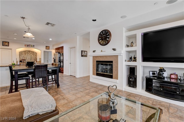 living room featuring a tile fireplace and built in features