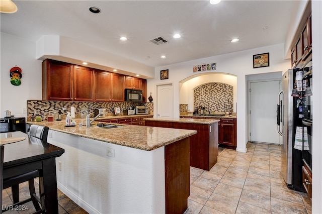 kitchen featuring sink, kitchen peninsula, a kitchen island, backsplash, and black appliances