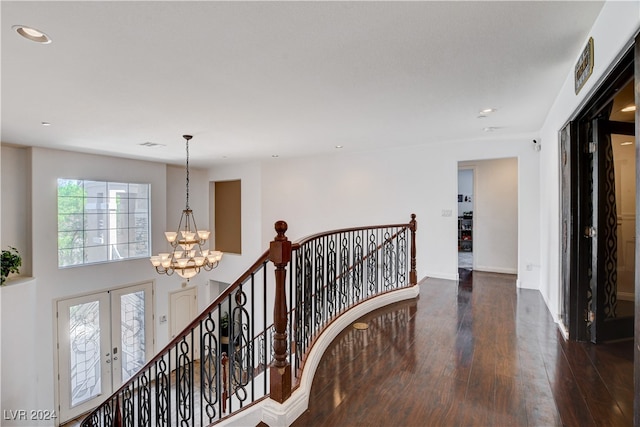 corridor with french doors, a chandelier, and dark wood-type flooring