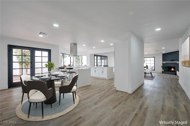 dining space featuring light hardwood / wood-style floors, french doors, and a brick fireplace