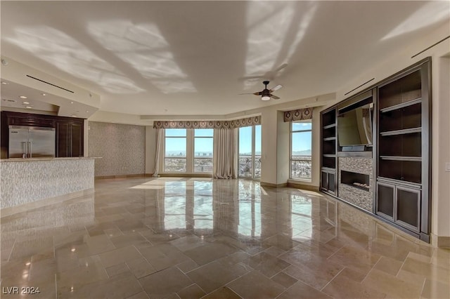 unfurnished living room with ceiling fan and built in shelves