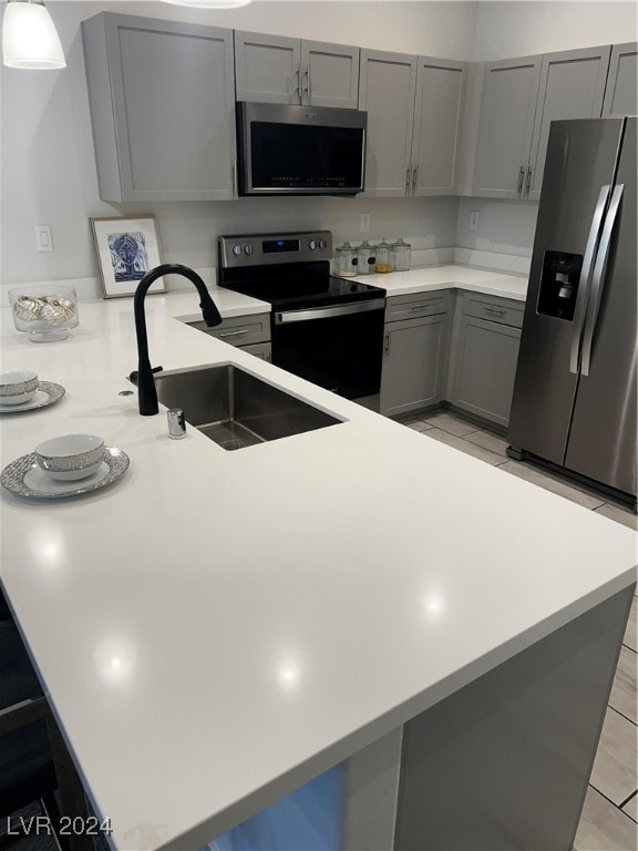 kitchen featuring gray cabinets, light tile patterned flooring, sink, kitchen peninsula, and stainless steel appliances