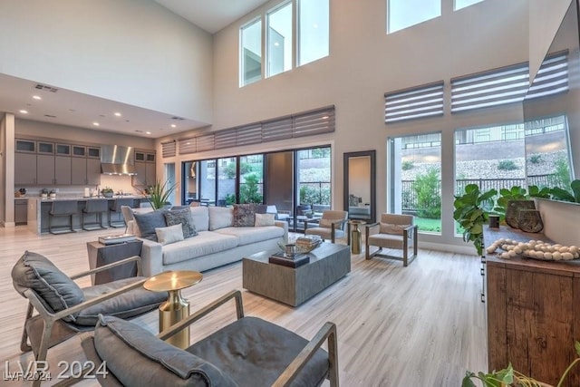 living room with light hardwood / wood-style flooring and a towering ceiling