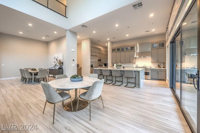 dining area with a towering ceiling and light hardwood / wood-style floors