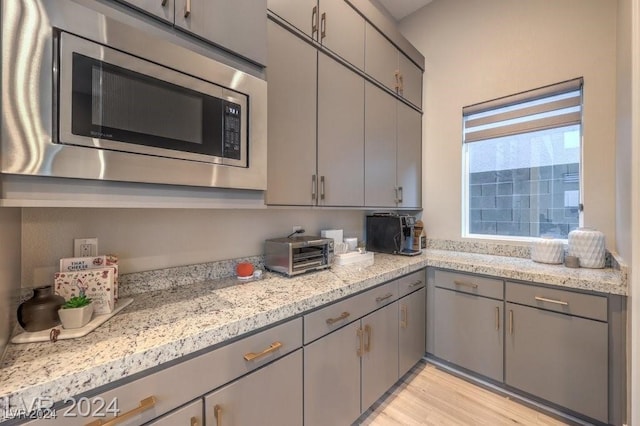 kitchen featuring gray cabinetry, light hardwood / wood-style floors, and stainless steel microwave