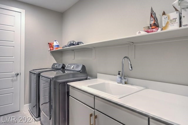 laundry room featuring washing machine and dryer, sink, light tile patterned floors, and cabinets