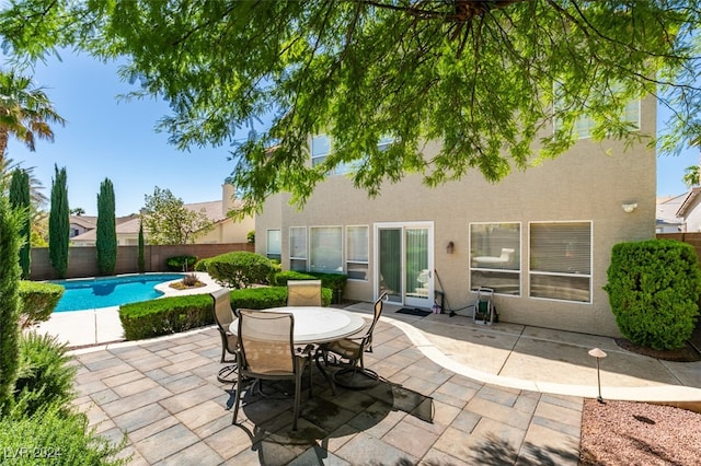 back of property with a fenced in pool and a patio area