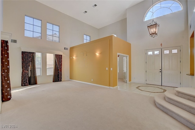 foyer featuring light colored carpet, a high ceiling, and an inviting chandelier