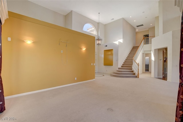 unfurnished living room featuring light colored carpet and a towering ceiling