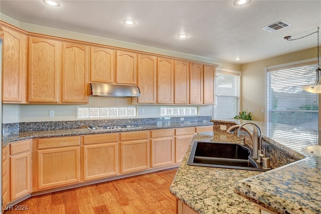 kitchen with light brown cabinets, sink, hanging light fixtures, stainless steel gas cooktop, and light wood-type flooring