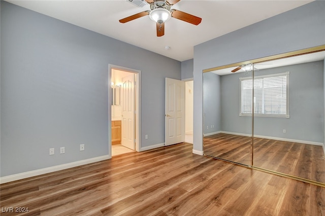 unfurnished bedroom with ensuite bath, ceiling fan, a closet, and hardwood / wood-style floors