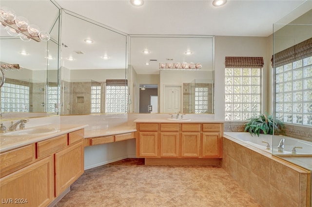 bathroom with tile patterned flooring, vanity, and a relaxing tiled tub