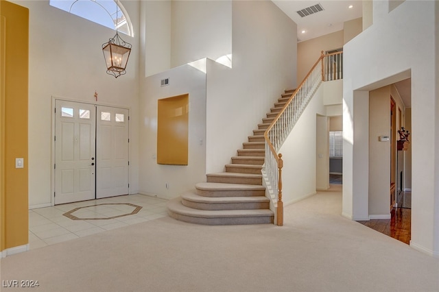 carpeted foyer with a towering ceiling