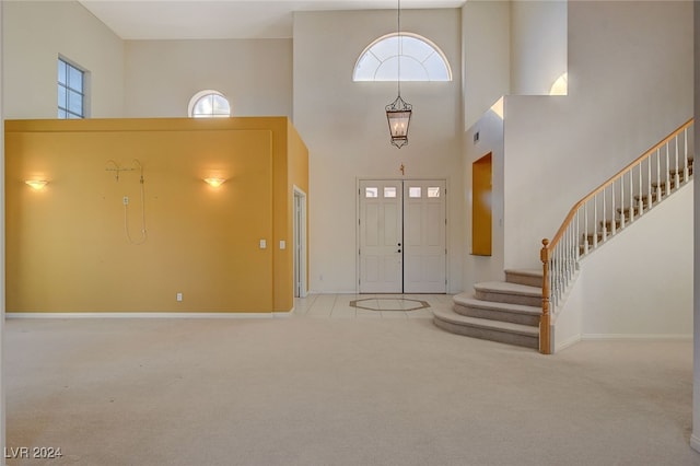 entryway with light carpet and a towering ceiling